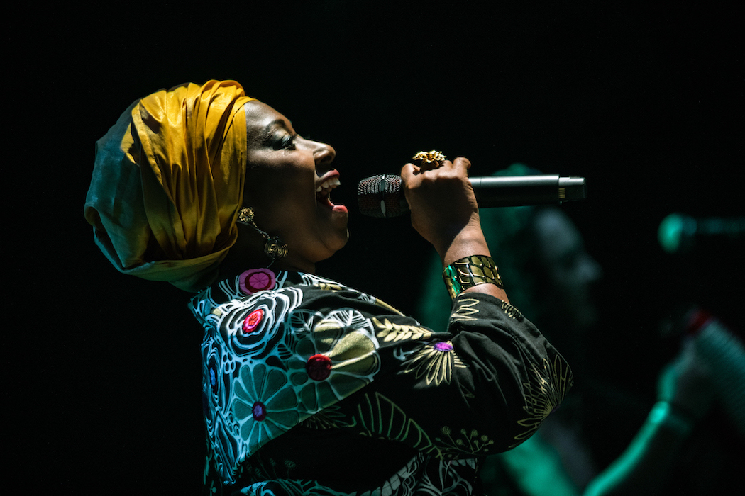 Foto lateral de mujer cantante afro con micrófono