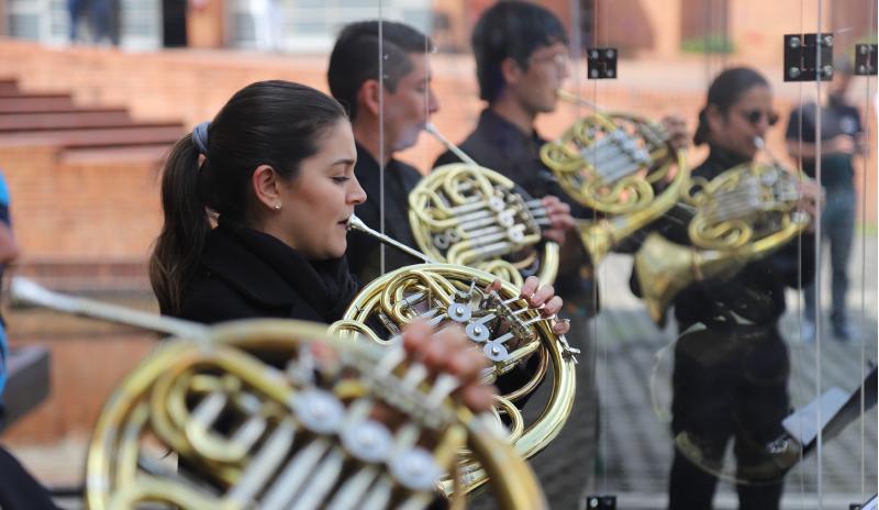 En primer plano se ve una mujer tocando la tuba