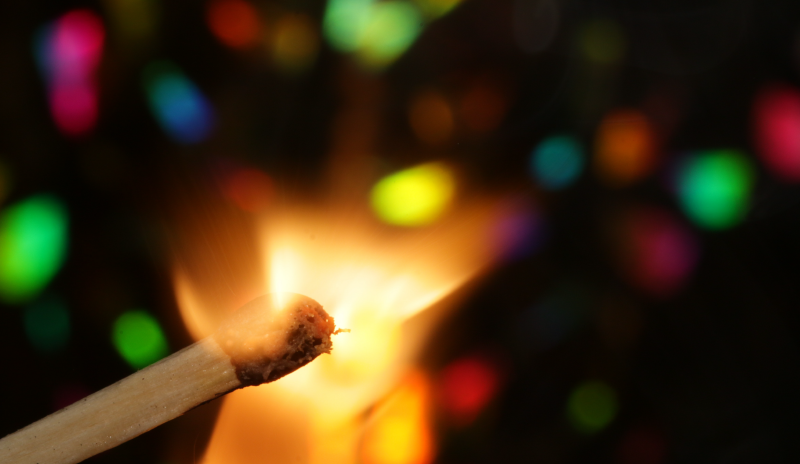 Fósforo encendido rodeado de luces de colores