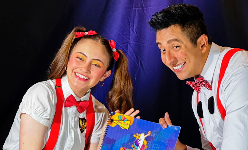 Dos artistas sonriendo y tomando un libro infantiol en la mano