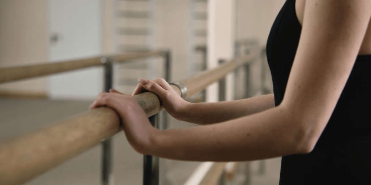 Bailarina apoyada en una barra.
