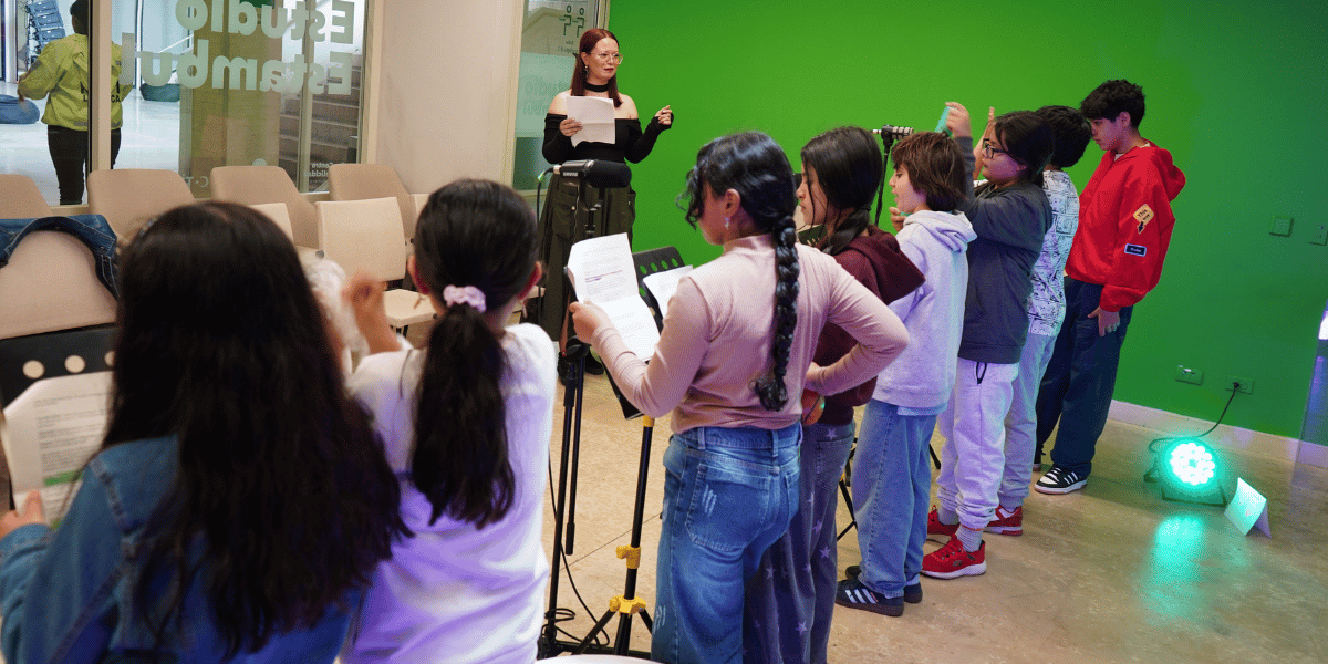 Fotografía de varias niñas y niños grabando su voz frente a un micrófono