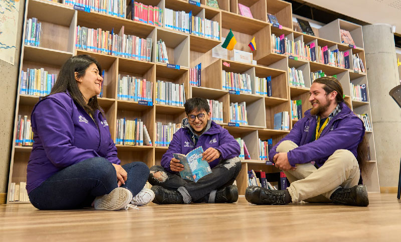 Personas sentadas en el piso de una biblioteca