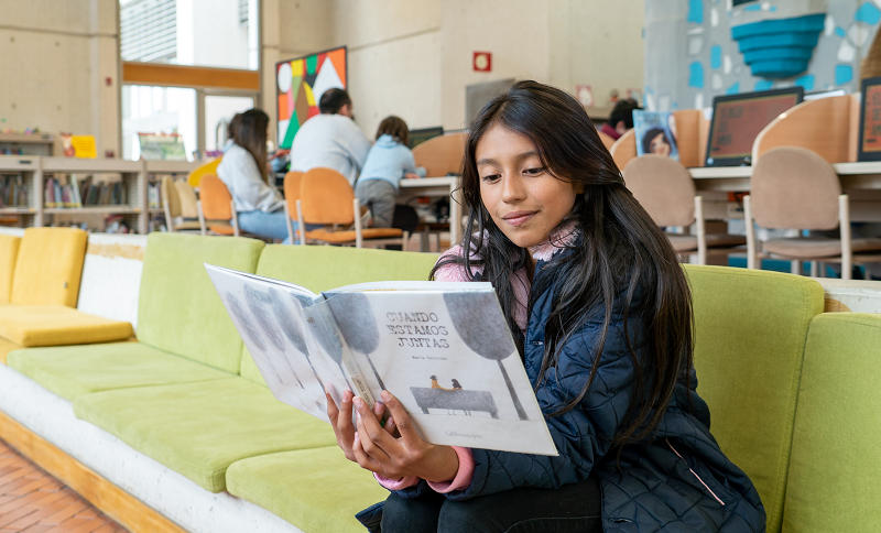 Nilña leyendo un libro en una biblioteca