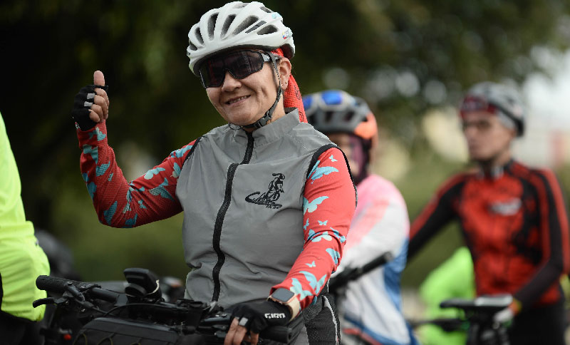 Mujer en bicicleta saludando a la cámara