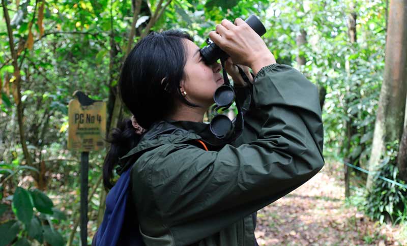 Mujer con unos binoculares en una caminata ecológica del IDRD