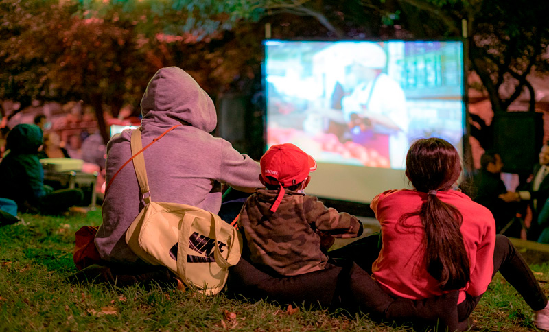 Señor y niña viendo una película al aire libre