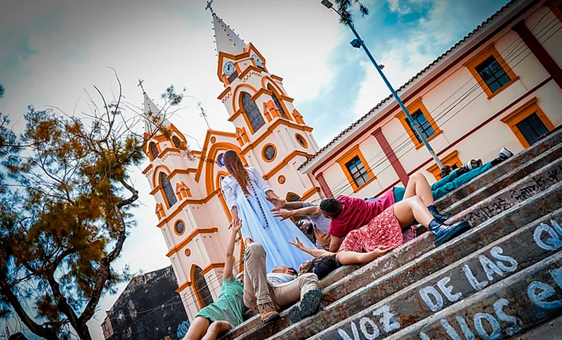 Actores y actrices al aire libre, actuando frente a una iglesia