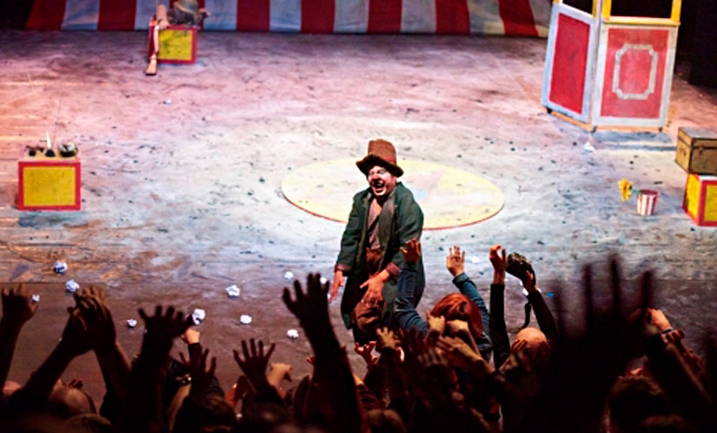 Payaso realizando una presentación en un circo con espectadores