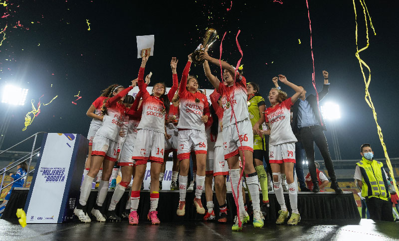 Mujeres de un equipo de fútbol alzando una copa