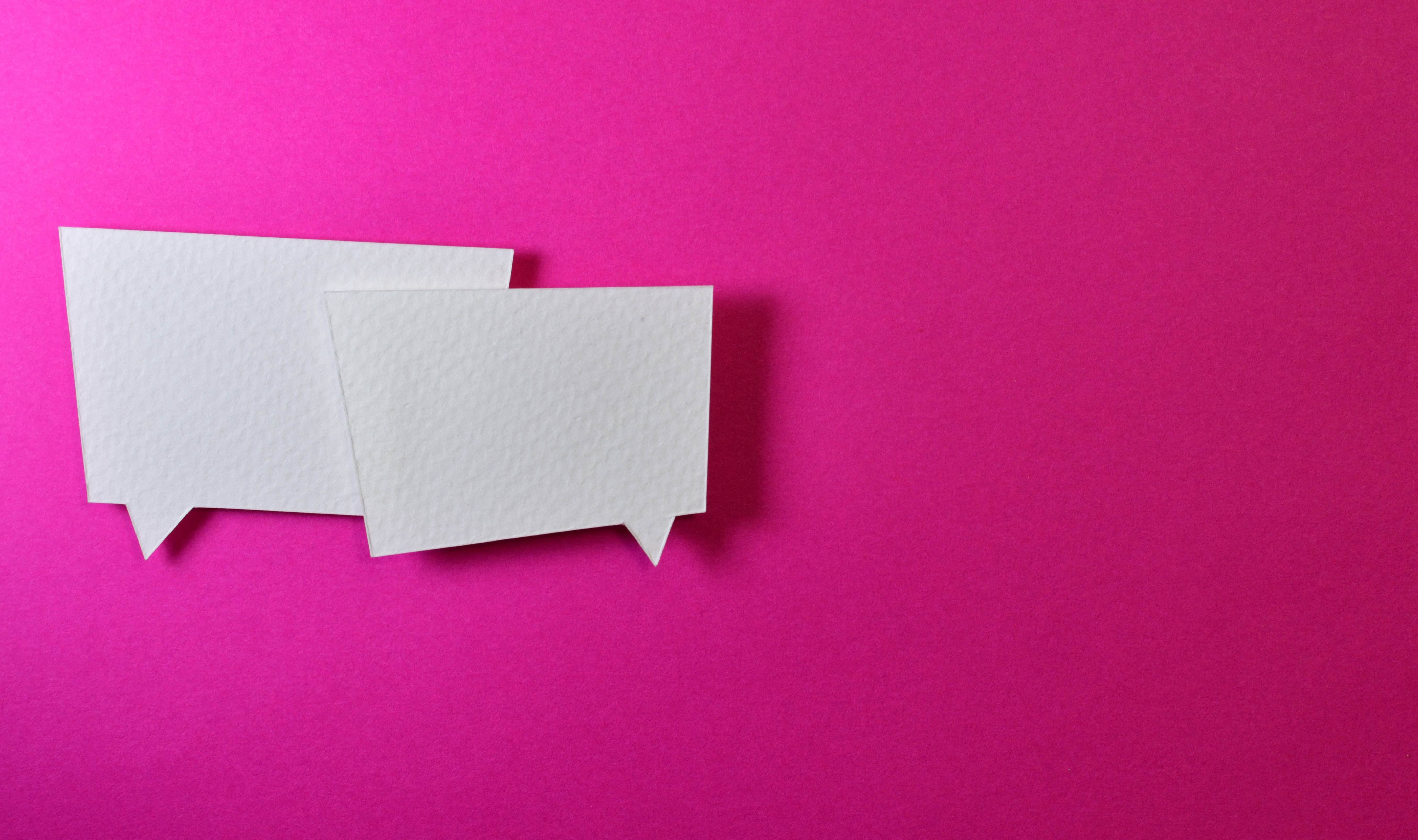 Dos viñetas de diálogo blancas sobre un fondo rosado
