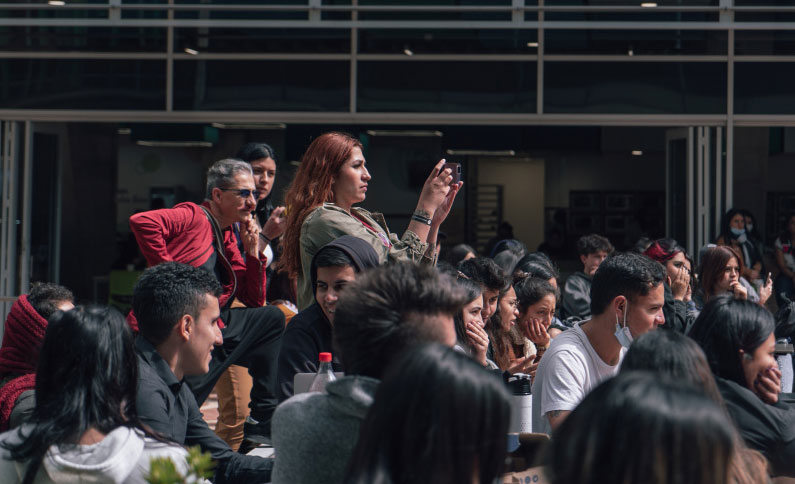 Mujer tomando fotos en un evento rodeada de personas