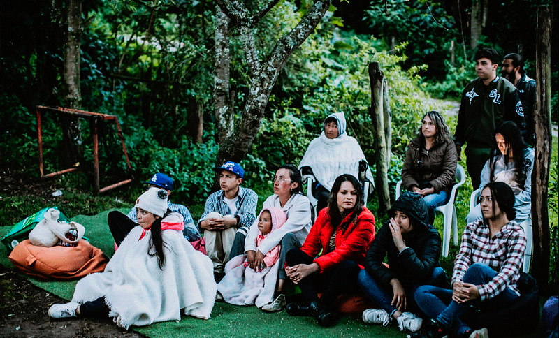 Grupo de personas sentadas alrededor de un ambiente de naturaleza