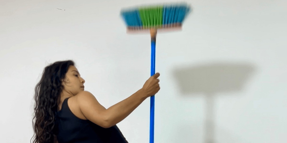 Mujer sosteniendo una escoba en lo alto