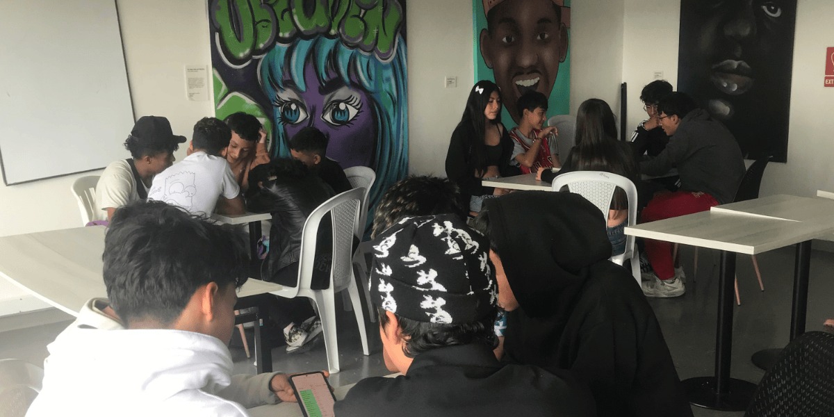 Asistentes al taller de rap alrededor de unas mesas.