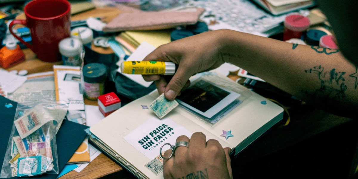Imagen de una mano pegando estampas en un cuaderno.
