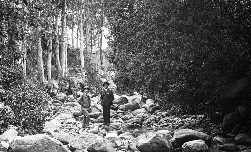Dos hombres parados sobre una roca en medio de un río