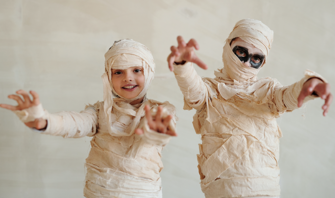 Dos niños disfrazados de momia. Al del lado izquierdo se le alcanza a ver la cara.