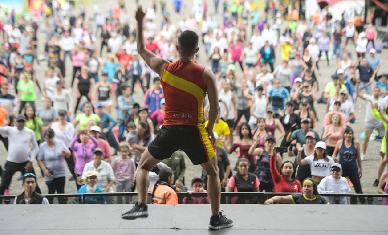 Instructor del Idrd en tarima con multitud de asistentes de fondo
