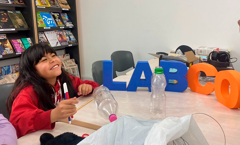 Niña en una mesa con unos marcadores en la mano