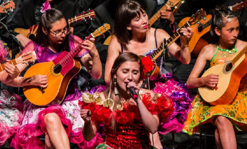 Mujer cantando rodada de otras mujeres tocando instrumentos