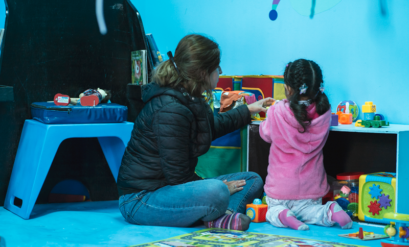 Mujer y niña jugando en una biblioteca