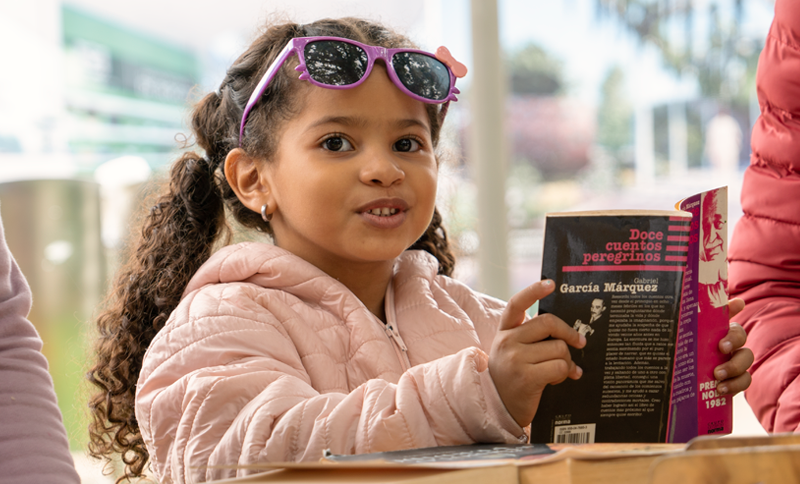 Niña leyendo un libro en la biblioteca