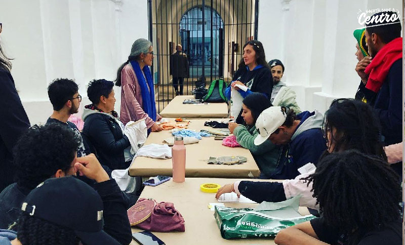 Jóvenes alrededor de una mesa escuchando información de una instructora