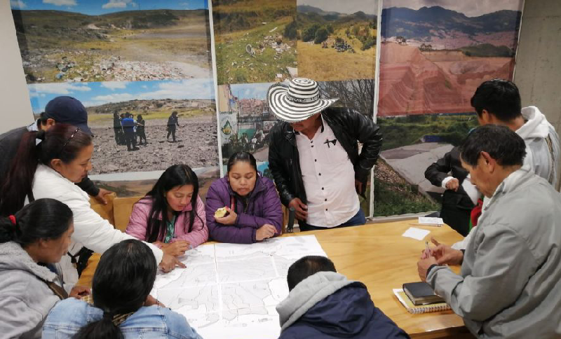 Grupo de personas reunidas alrededor de un documento puesto en una mesa