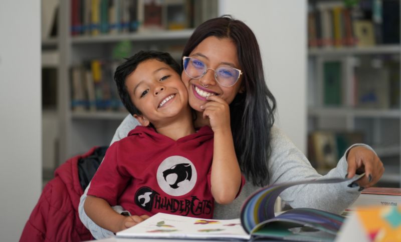 Madre e hijo posando sonrientes en una biblioteca