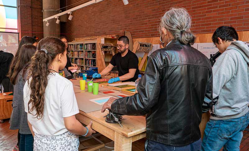 Personas rodeando una mesa siguiendo instrucciones de un capacitador
