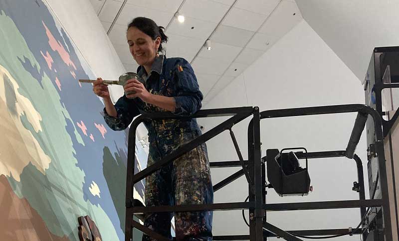 mujer realizando una pintura en una pared