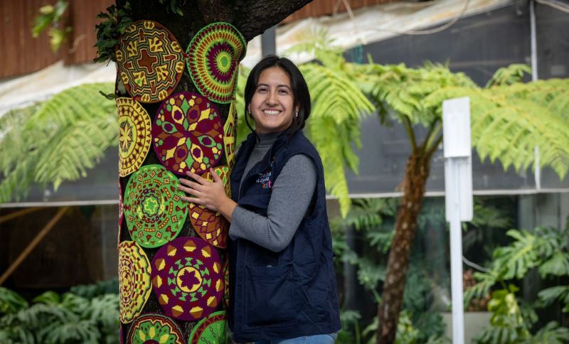 Mujer abrazando un árbol tejido por mujeres Wayúu
