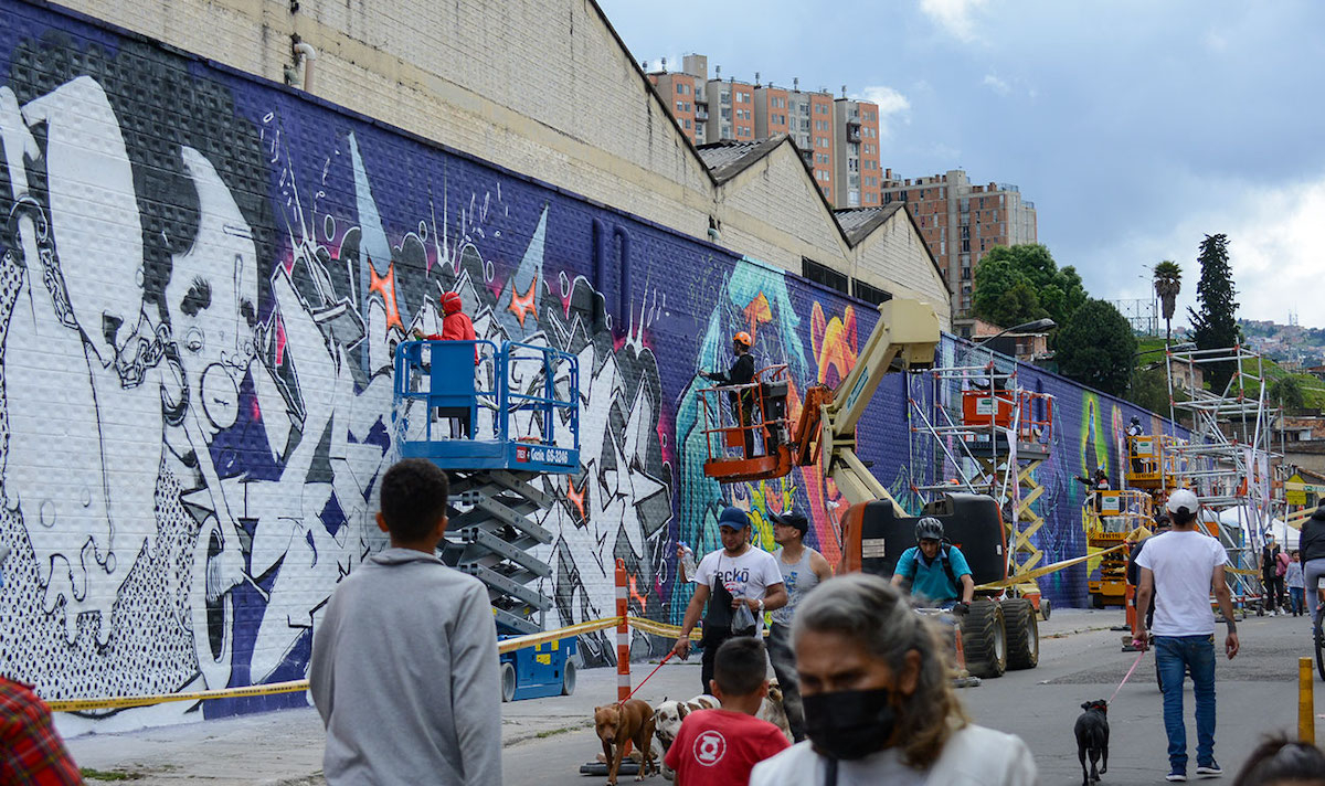 Artistas haciendo grafitis en un muro sobre plataformas
