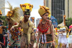 dos artistas en el desfile, personificando a leones