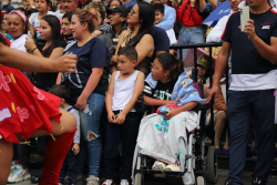 Niña en silla de ruedas observa el defile