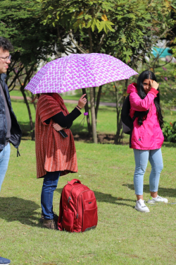 Una ciudadana con sombrilla, escucha guía de recorrido