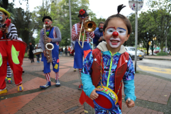 Niño artista con traje de payaso toca instrumento