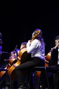 Niña de orquesta sinfónica ejecuta violonchelo