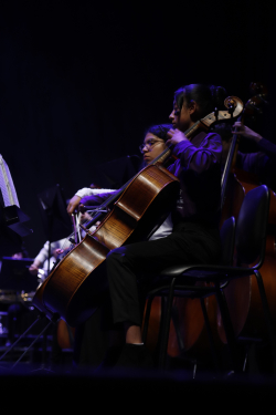 Niña de orquesta sinfónica ejecuta violonchelo