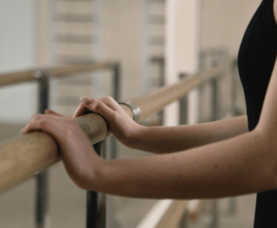 Mujer apoyada en barra de ballet.