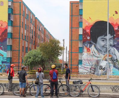 Mural de niño sonriendo sobre pared de conjunto residencial, personas observan