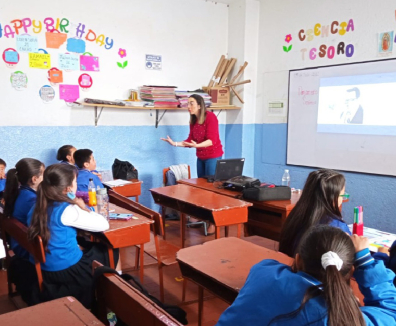 profesora dictando una clase a un grupo de niñas y niños