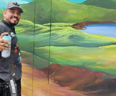 Hombre con aerosol en la mano pintando un mural