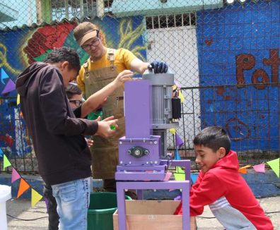 Niños con un profesor aprendiendo a el funcionamiento de una máquina de reciclaje