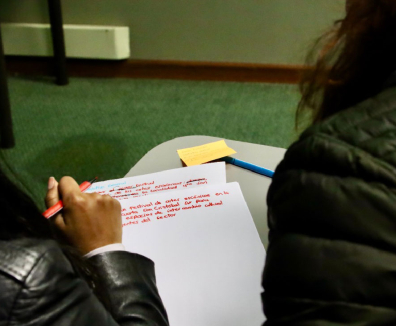 dos jóvenes mirando un cuaderno y escribiendo