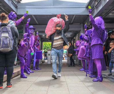 Personas vestidas de violeta saludando a ciudadano