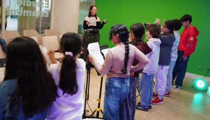 Fotografía de varias niñas y niños grabando su voz frente a un micrófono