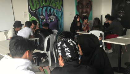 Asistentes al taller de rap alrededor de unas mesas.