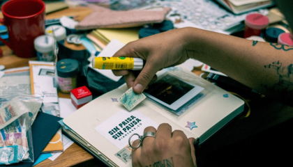 Imagen de una mano pegando estampas en un cuaderno.